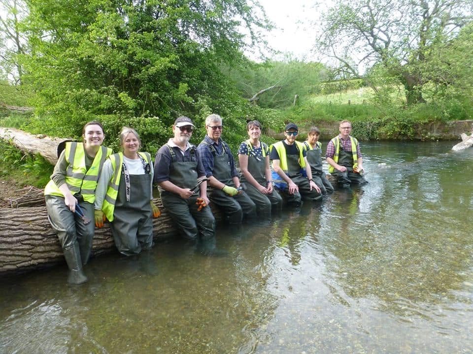 Local volunteers gathered by the river in the rural Wiltshire countryside near Chilton Foliat