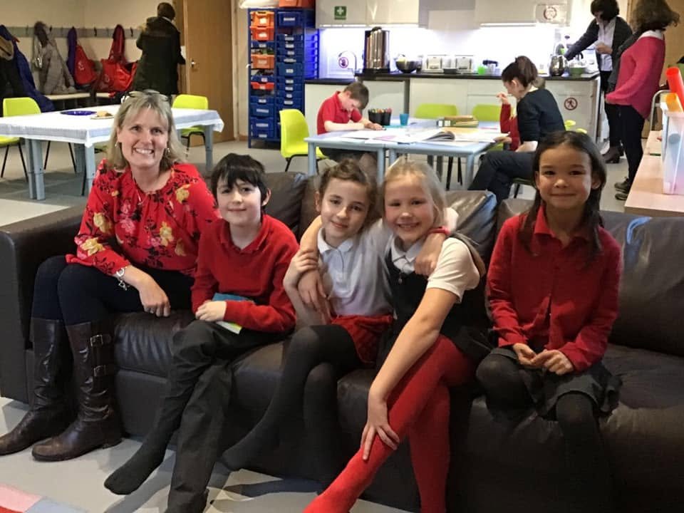 A teacher and children relaxing on sofas inside the bright Clubhouse interior